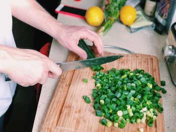 Midsection of person preparing vegetables on cutting board