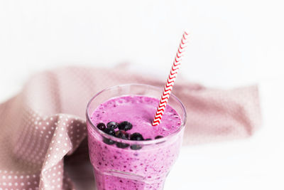 Close-up of drink with pink glass against white background