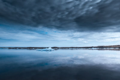 Iceberg floating in sea against sky at dusk