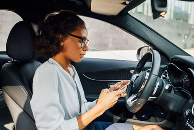 Woman using phone while sitting in car