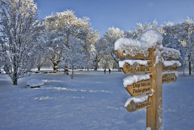 Wooden directional sign on snow covered field
