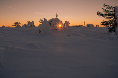 Scenic view of snow covered land against sky during sunset