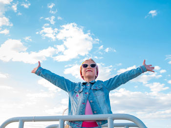 Little girl raised arms blue sky. happy child smiling flying in the air. lifestyle freedom happiness