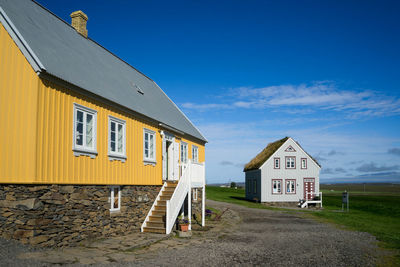 View of road by building against blue sky