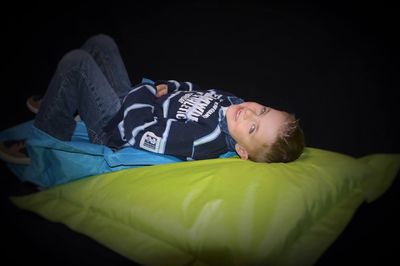 Portrait of boy relaxing on air bed in darkroom