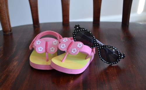 Close-up view of a pink pair of sandals and black shades on a table