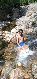 Full length of shirtless man standing on rock