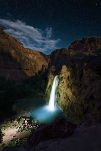 Scenic view of waterfall against sky at night