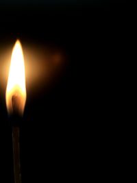 Close-up of lit candle against black background