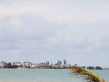 Sea by buildings against sky in city