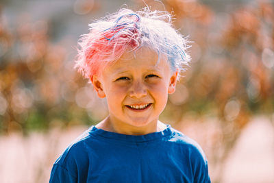 Portrait of young boy with colored hair smiling at camera