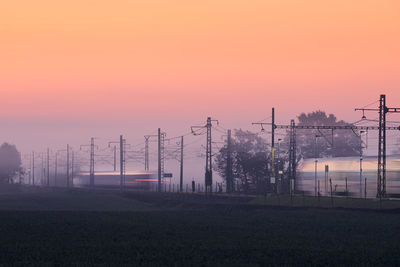 Electricity pylon on field against sky during sunset