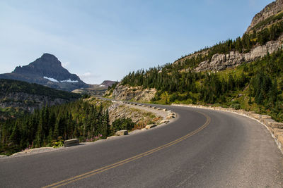 Road amidst trees and mountains against sky