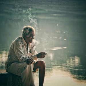 Thoughtful senior man smoking by lake