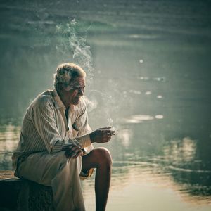 Man sitting on table by water