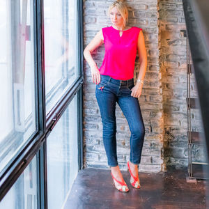 Woman looking through widow while standing against wall