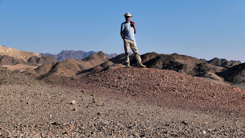 Senior man standing on mountain against clear sky