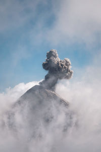 Low angle view of smoke emitting from volcanic mountain against sky