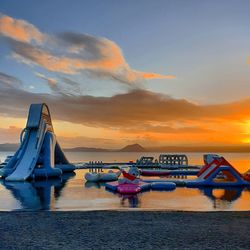 Boats moored in sea against sky during sunset