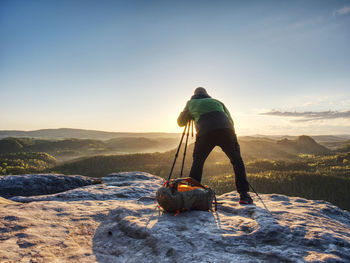 Artist set camera and tripod to photograph the sunrise on a rocky summit. artist works in nature