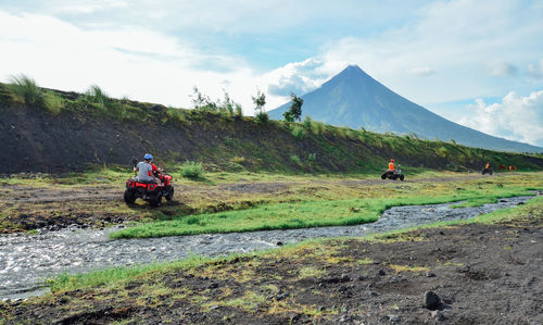 People riding motorcycle on mountain against sky