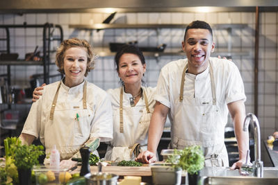 Portrait of smiling confident chefs standing at kitchen in restaurant