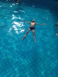 High angle view of shirtless boy swimming in pool