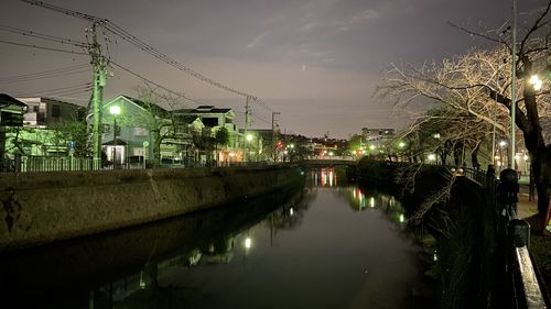 Canal amidst illuminated city against sky at night