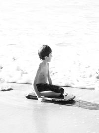 Full length of man sitting at beach on sunny day