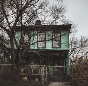 Low angle view of bare trees and building against sky