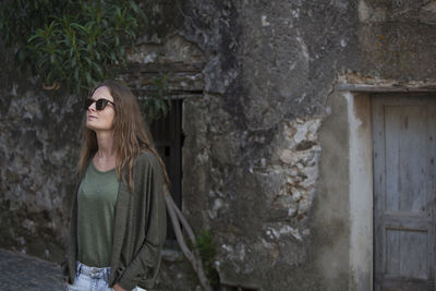 Woman wearing sunglasses standing against wall