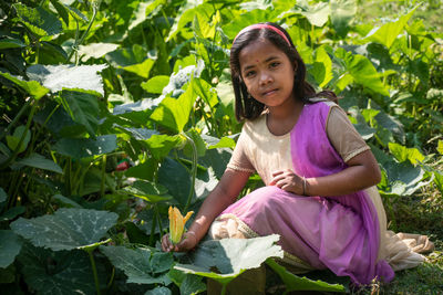 Portrait of young woman standing amidst plants