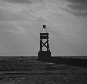Lighthouse by sea against sky