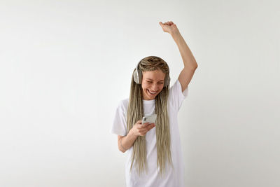 Happy young woman standing against white background