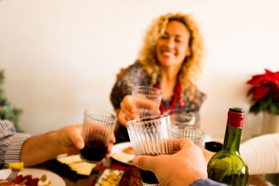 People toasting wine glass while having lunch sitting at home