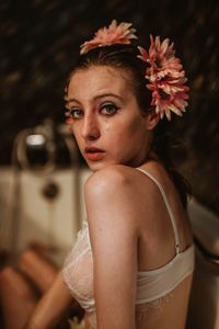 Side view portrait of beautiful young model wearing flowers while sitting in bathtub