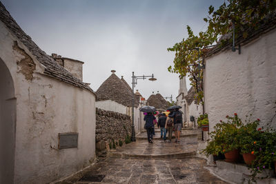 Tourists in the rain as they visit the streets of the alberobello village, italy