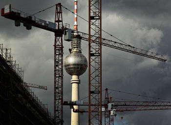 
television tower framed by construction cranes