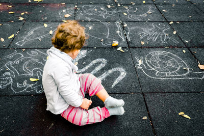 High angle view of child sitting on street