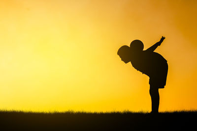 Silhouette man standing on field against sky during sunset