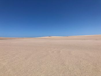 Scenic view of desert against clear blue sky