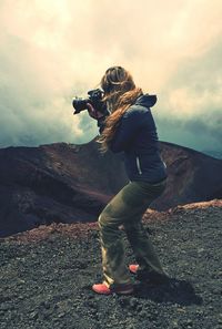 Full length of woman standing on rock against cloudy sky