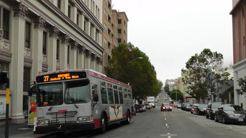 Cars on city street against sky