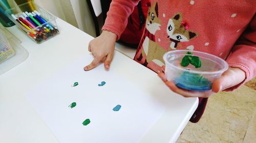 Midsection of boy painting on paper at table