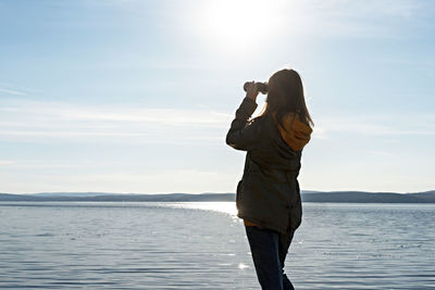 Man photographing at camera by sea against sky