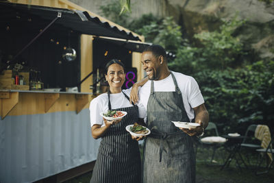 Male owner looking at female colleague with food standing by truck