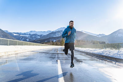Germany, bavaria, sportive man running on a road in winter