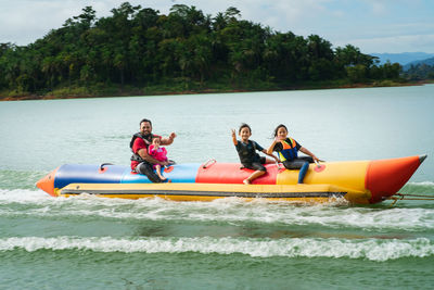 Smiling family sitting on boat in sea