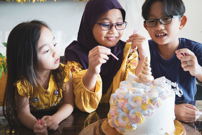 Siblings decorating birthday cake at home