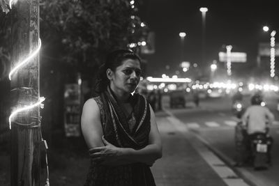 Portrait of young woman standing in city at night